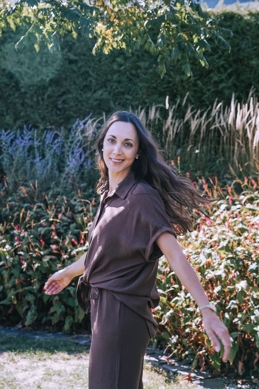 Sophie dreht sich lachend im blühenden Garten, die Haare fliegen