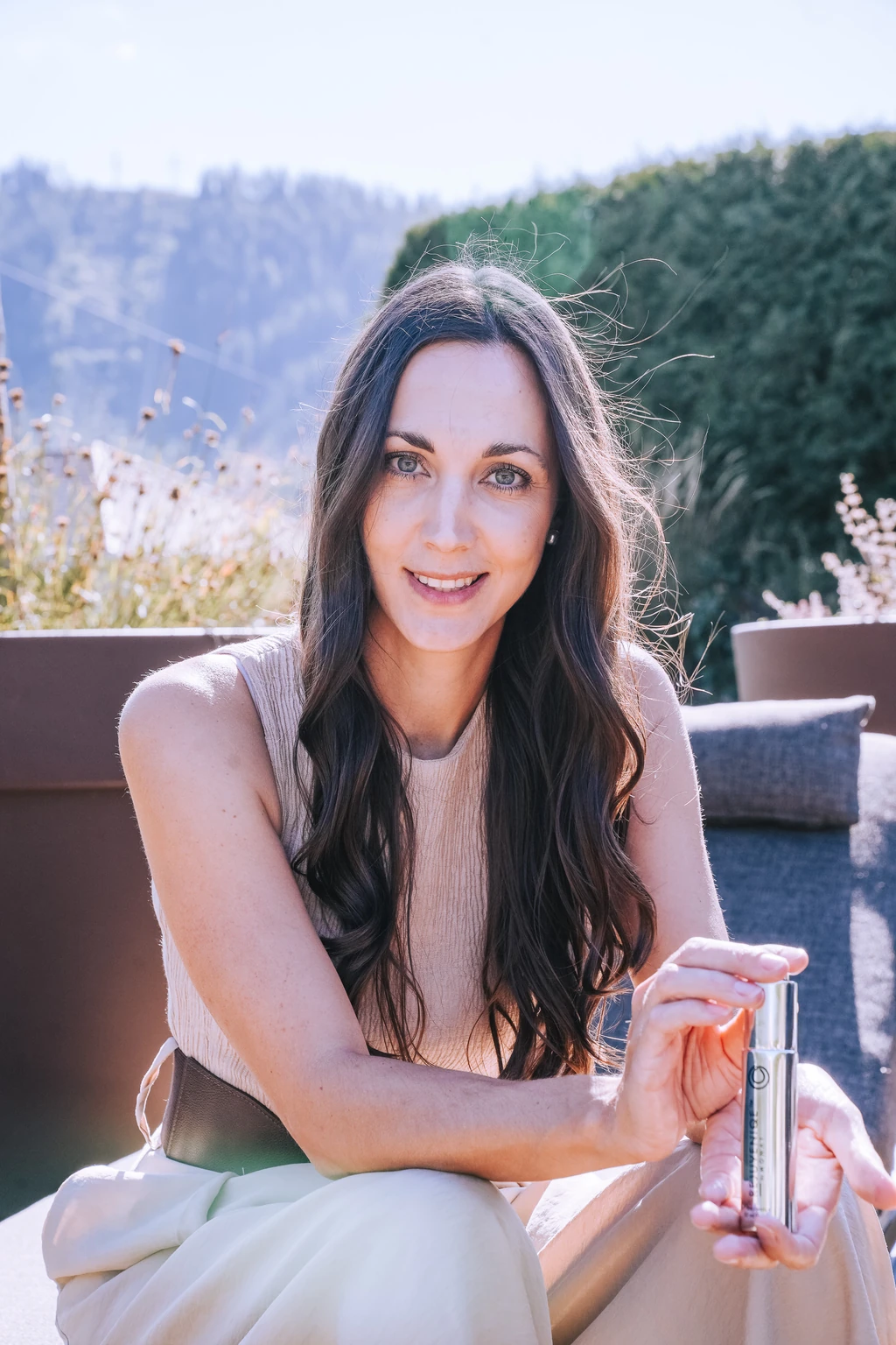 Sophie Täubl lächelt in der Sonne und hält ein MONAT Kopfhaut-Serum